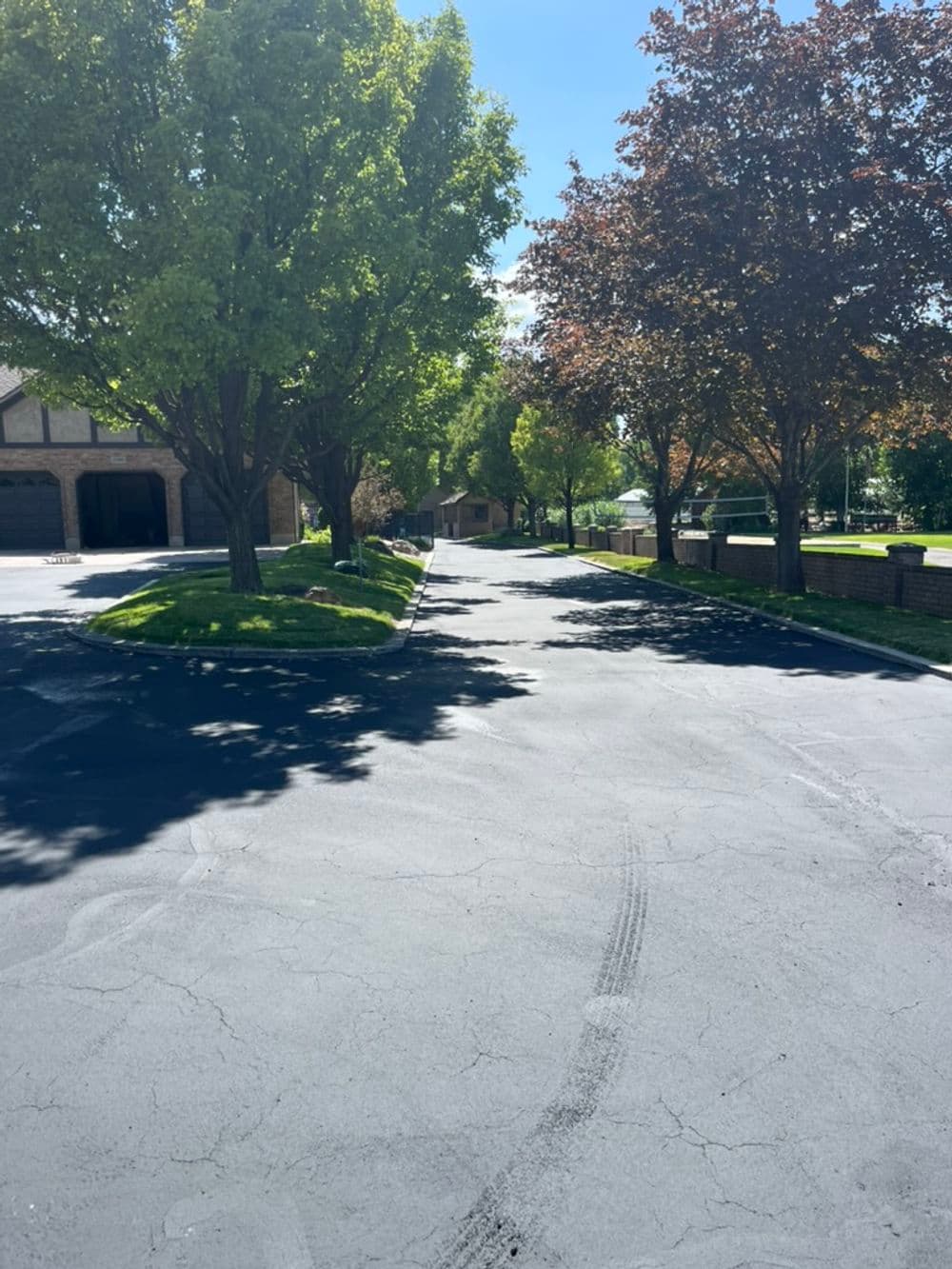 Tree-lined residential street with freshly paved asphalt and vibrant autumn foliage.