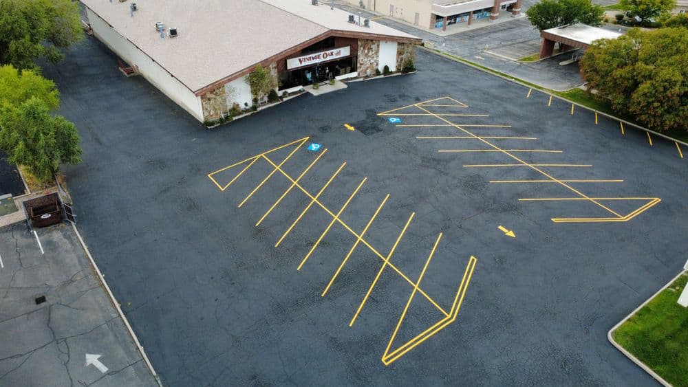 Aerial view of a vacant parking lot outside a building with yellow-striped spaces.